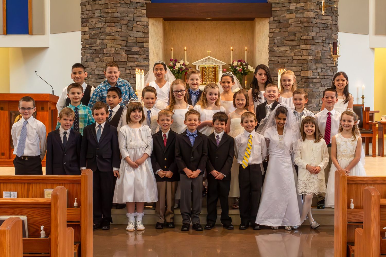 First Communion group photo with children and adults in church.