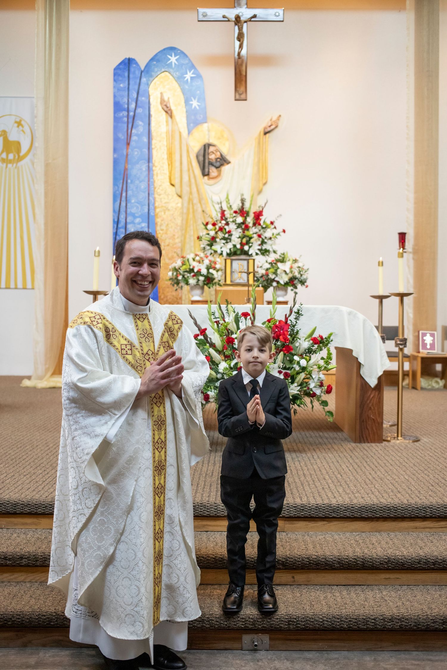 A religious ceremony takes place at an altar decorated with floral arrangements and religious imagery.