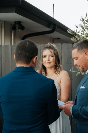 Outdoor wedding ceremony with couple exchanging vows against natural foliage.