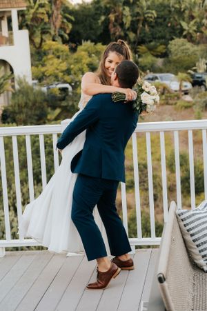 Couple embracing on an outdoor white porch deck during sunset.