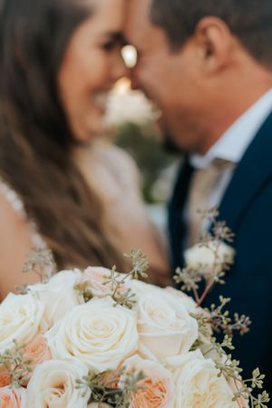 Soft focus wedding portrait with white roses and delicate floral arrangements in foreground.