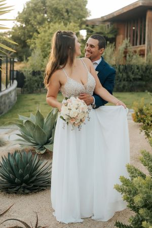 Wedding couple poses along garden path with decorative succulents and natural landscape.
