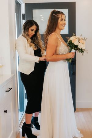 Wedding dress fitting showing detailed beadwork and flowing white gown being adjusted.