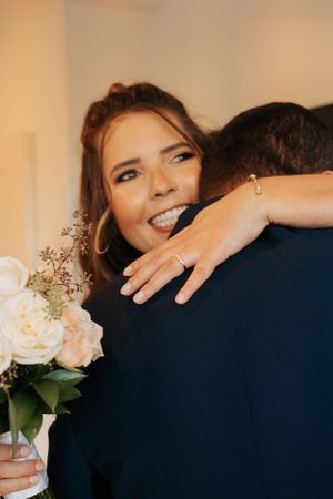 Emotional embrace showing new wedding ring and white rose bouquet.