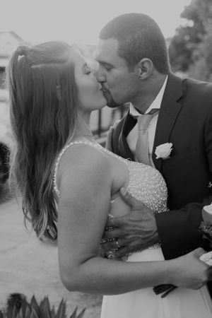 A romantic black and white wedding photo of a couple sharing their first kiss as newlyweds.