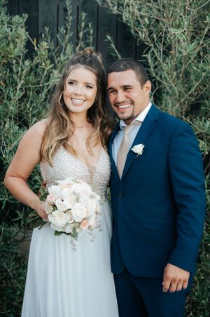 Wedding portrait in garden setting with couple in navy suit and beaded white gown.
