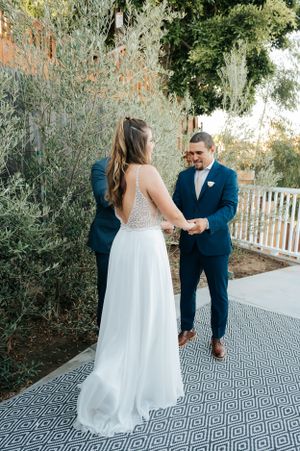 Wedding ceremony on an outdoor patio with geometric pattern rug and lush greenery backdrop.