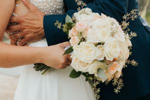 Elegant white and cream rose wedding bouquet with delicate greenery accents.