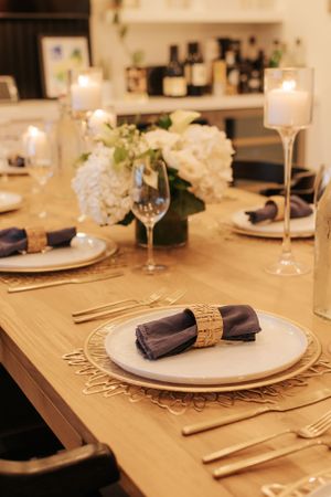 Elegant table setting with white plates, purple napkins and gold accents for a formal dinner.