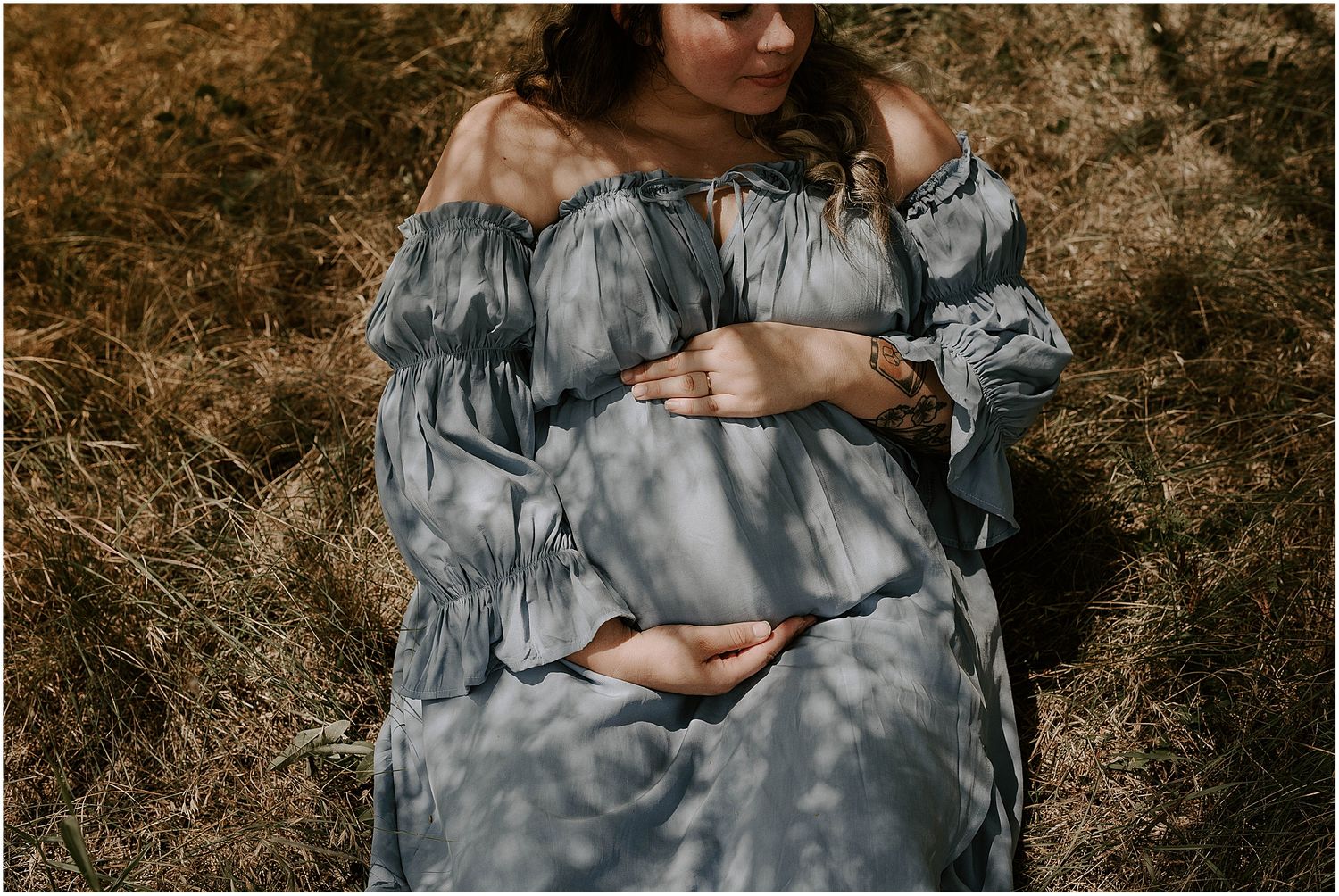 Close-up maternity portrait showcasing the gentle curves of pregnancy in a textured grey dress.