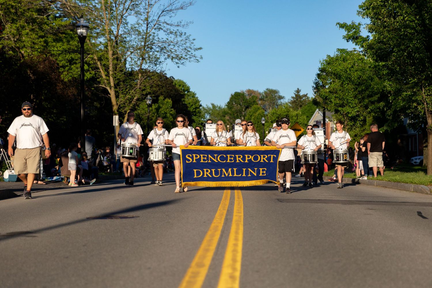Marching band and drum line performing in street parade on sunny afternoon.