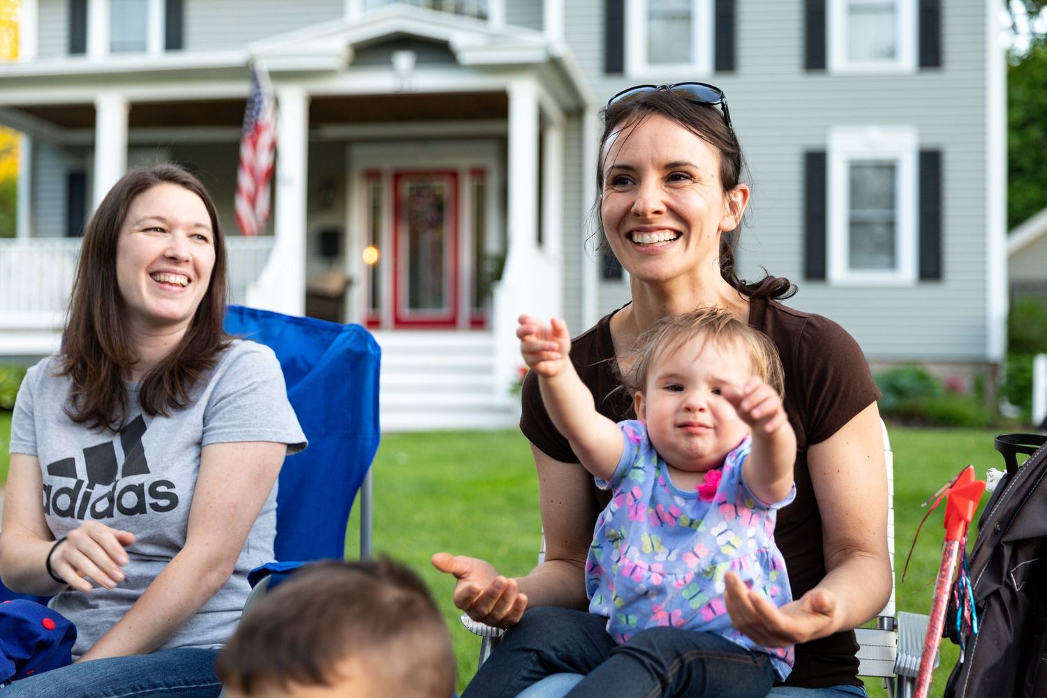 Group of people enjoying outdoor activities on residential porch steps.
