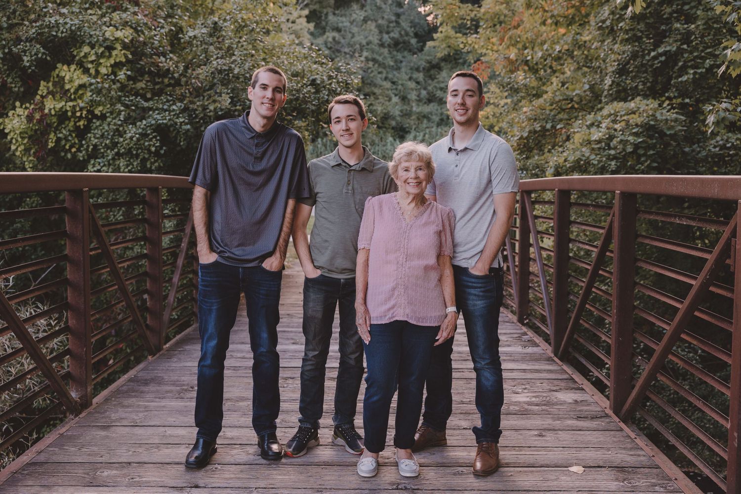 Four people standing together on wooden bridge for family portrait.