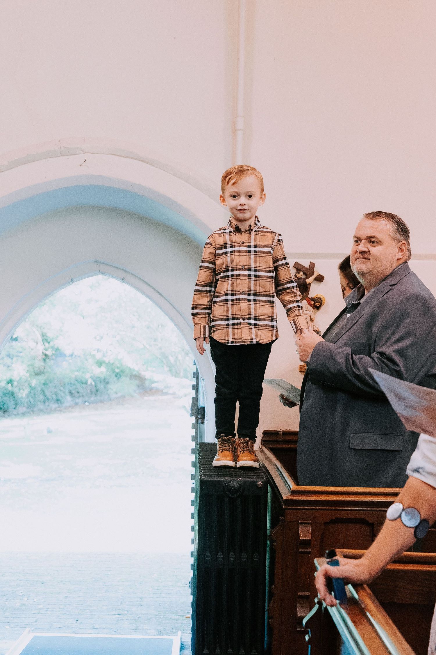 Church service with attendees seated in pews under arched windows.