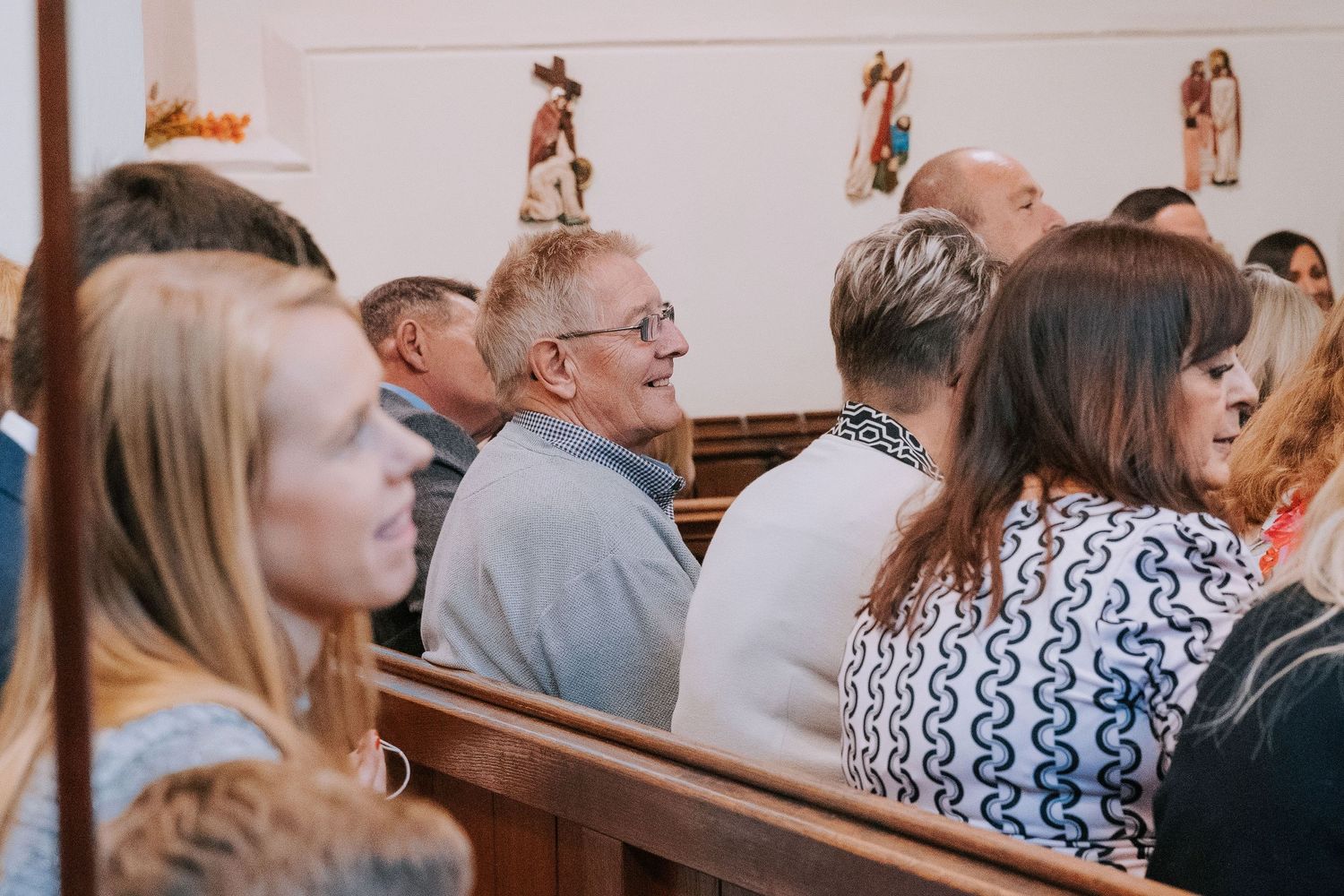 Congregation members sitting attentively in traditional wooden church pews.