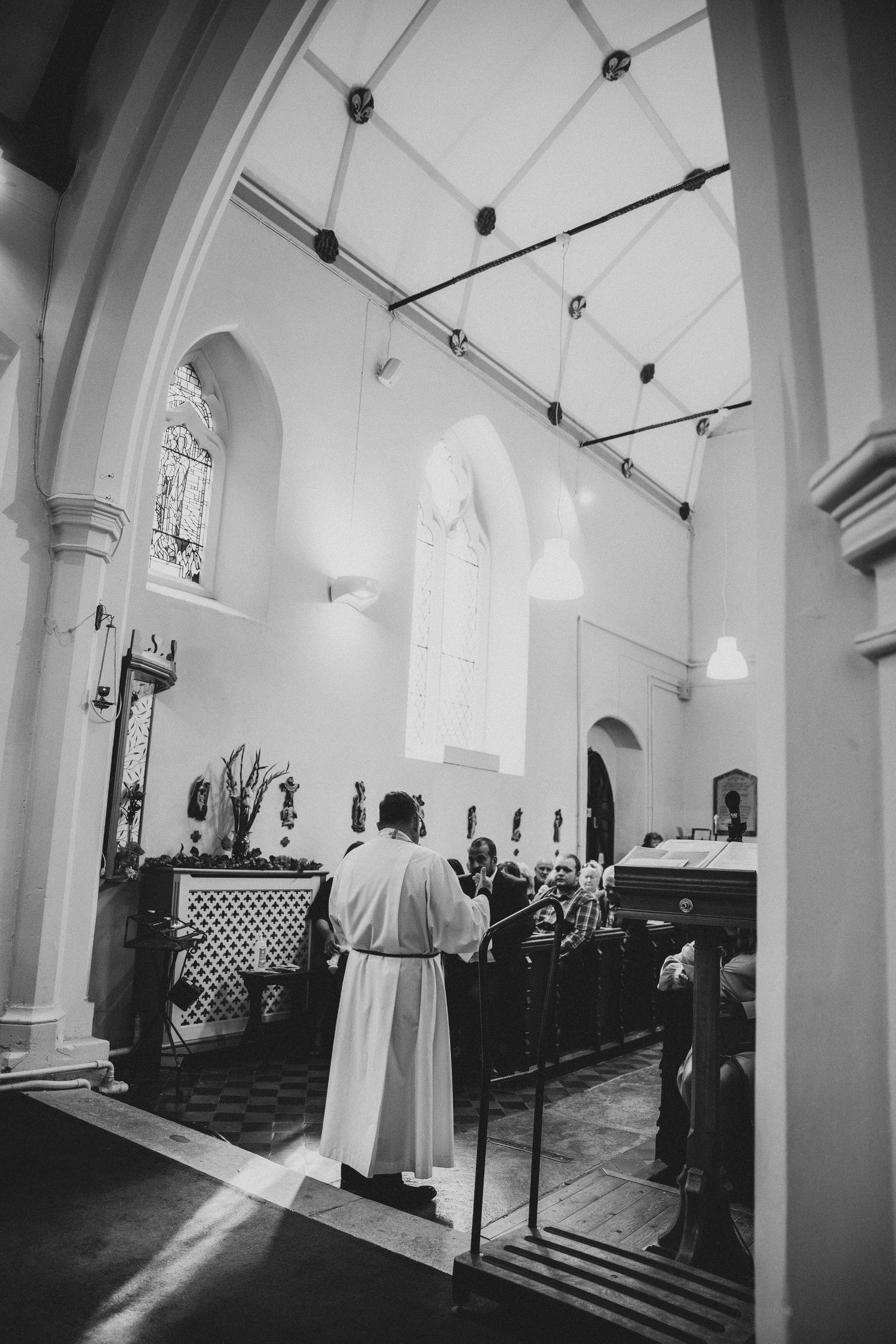 Black and white photograph of a church interior with vaulted ceilings and dramatic lighting.