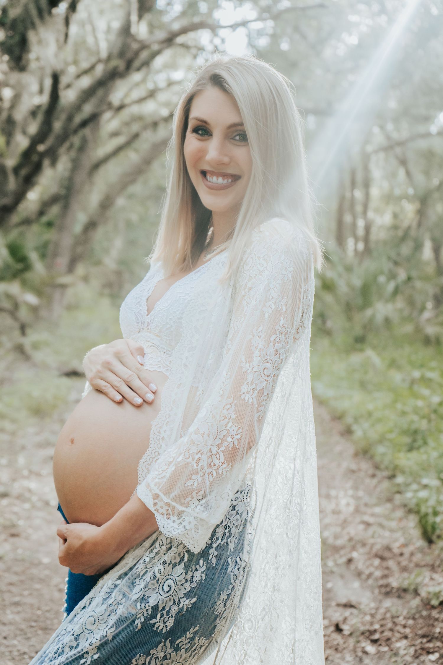 Outdoor Maternity Session at Thatcher Park, Lithia, FL; woman holding her pregnant belly bathed in sunlight