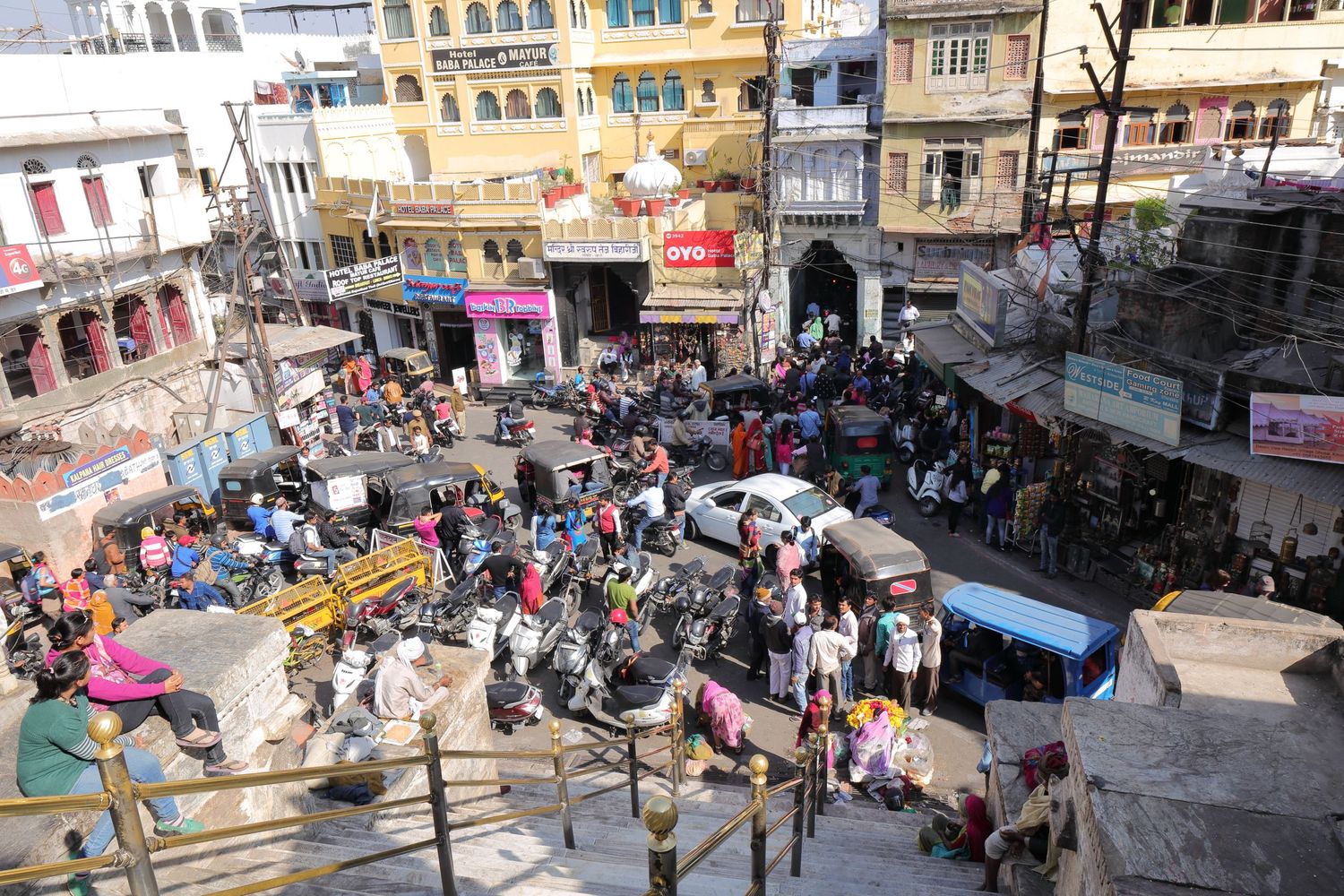 Busy street market scene in Jaipur with crowded shops and colorful buildings.