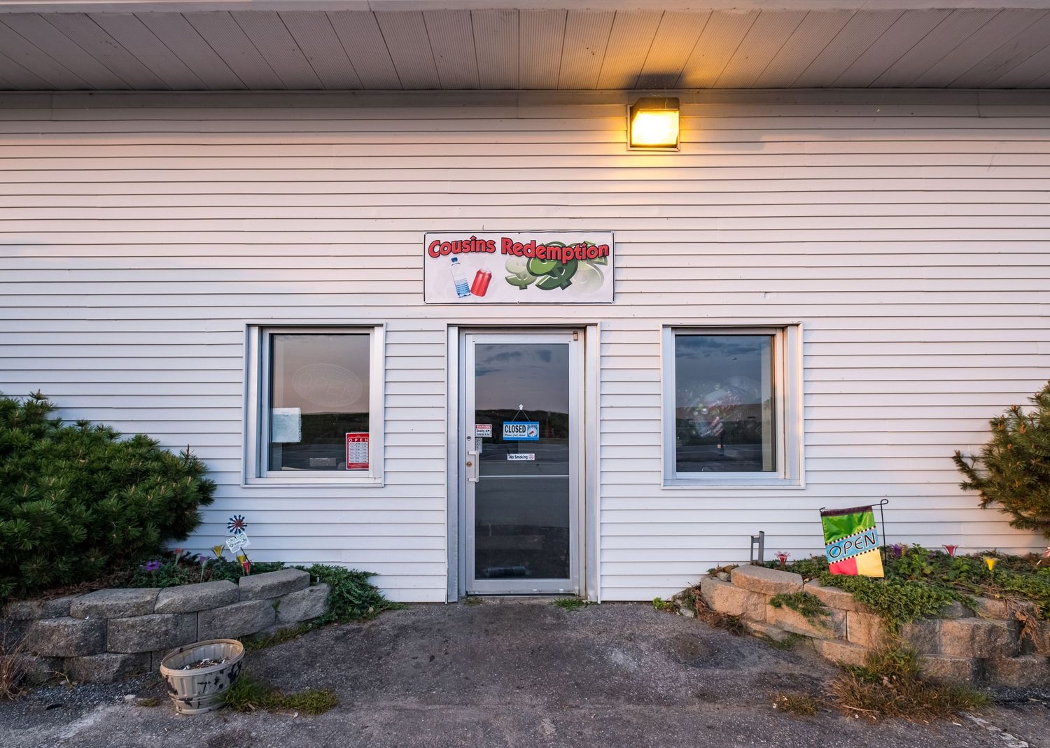 White siding building exterior with centrally placed door and windows at dusk.