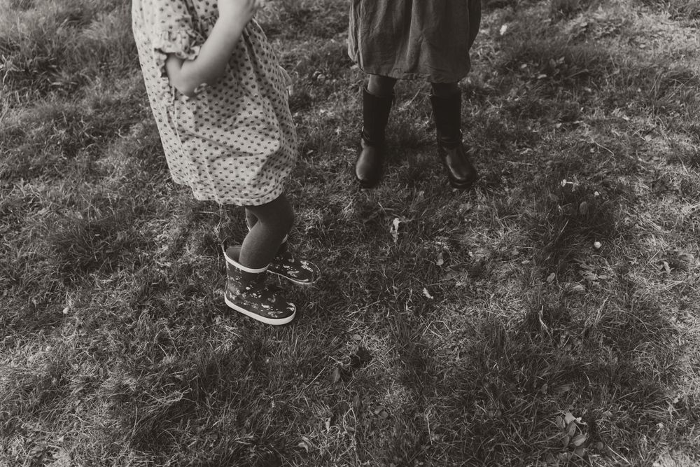 Black and white photo showing two pairs of feet standing in grass.