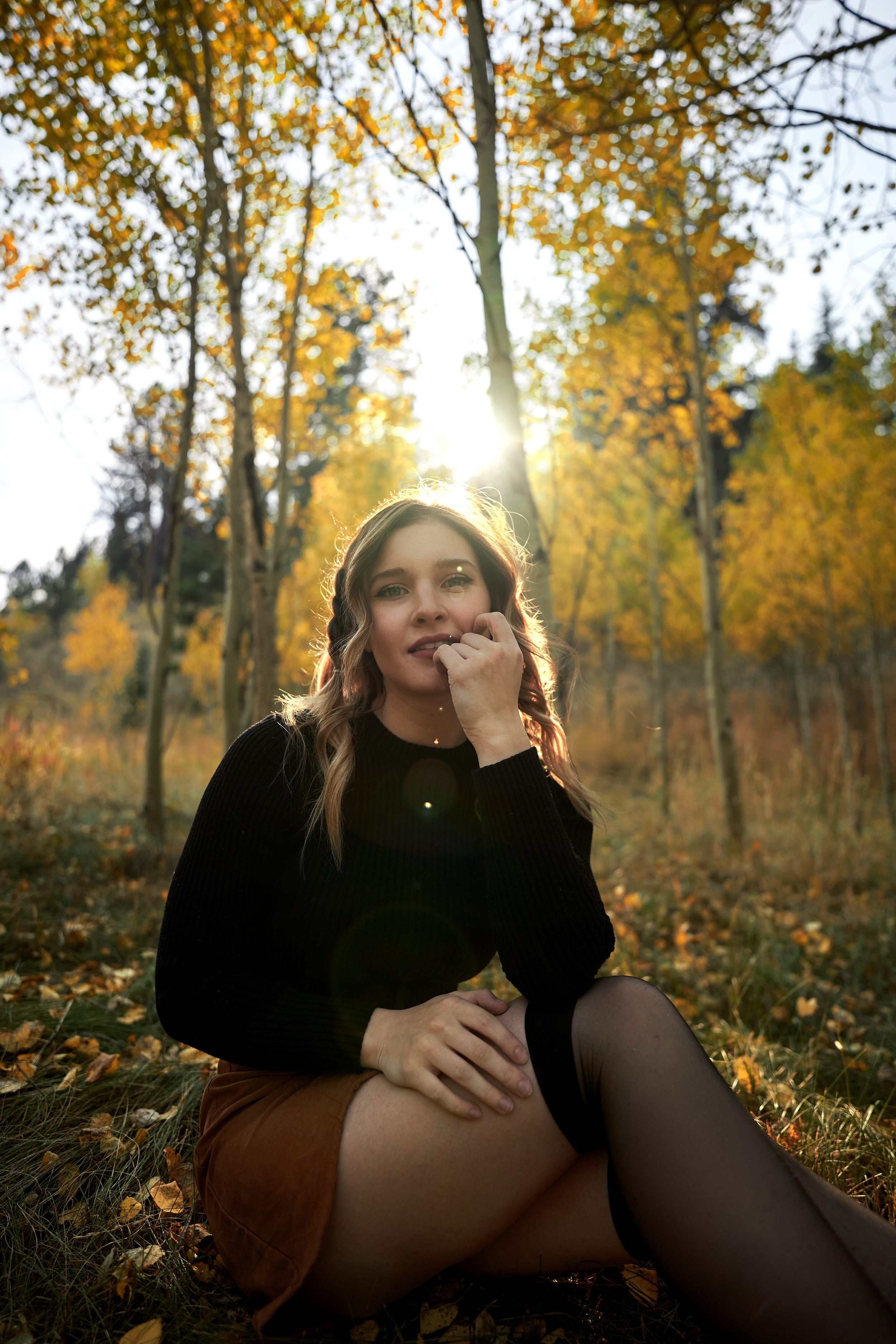 Artistic autumn photoshoot among yellow aspen trees with dramatic lighting.
