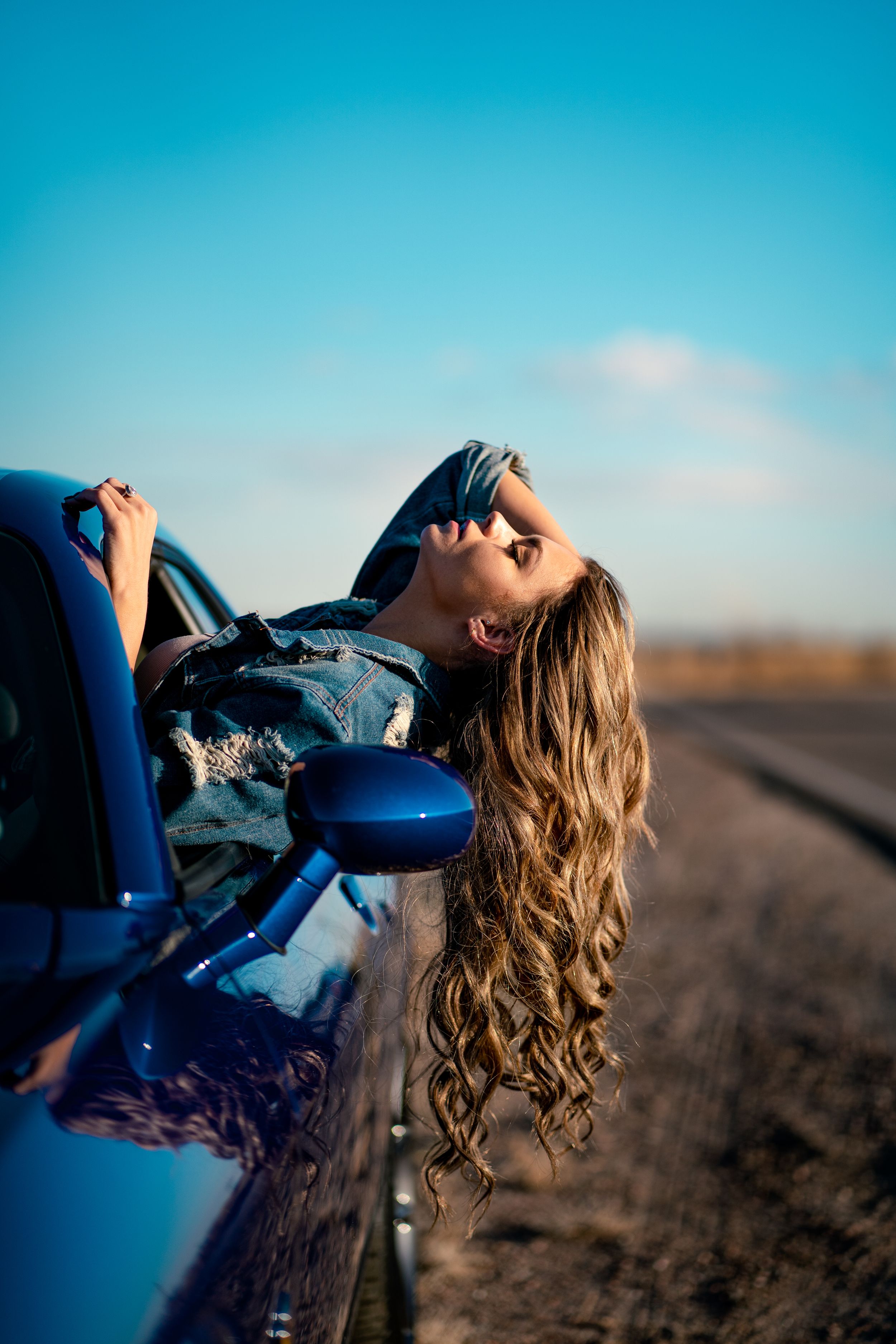 Dramatic car photoshoot against blue sky with artistic poses.