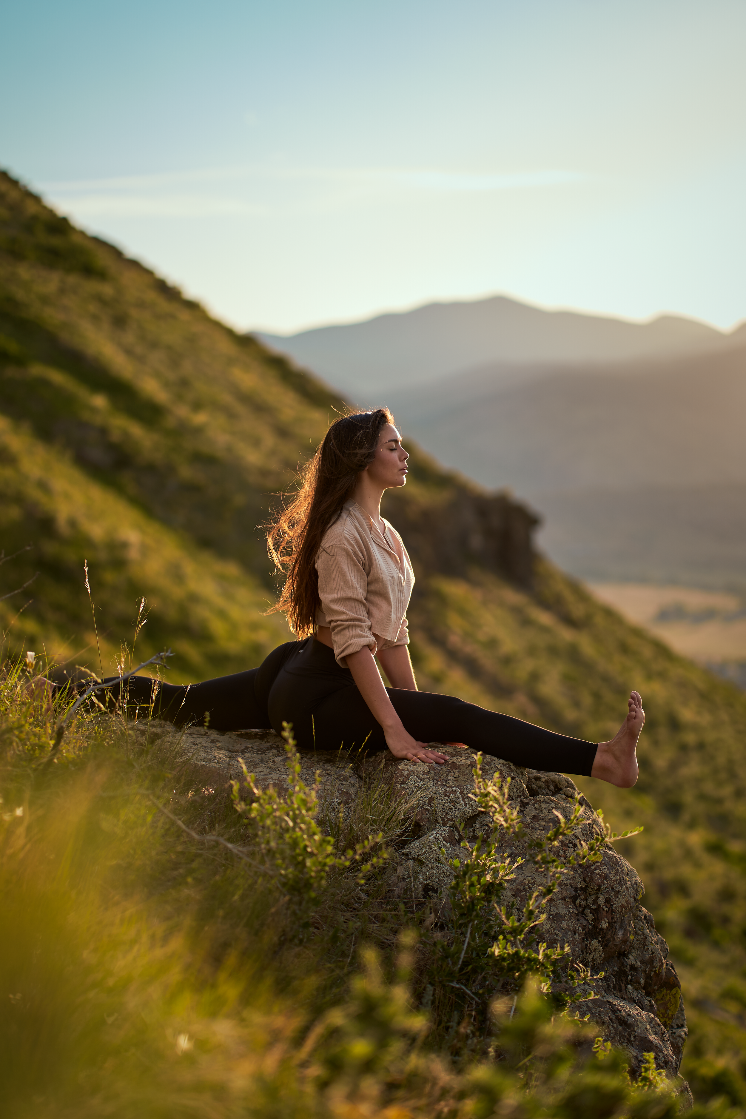 Peaceful yoga pose on mountain cliff during golden hour sunset.