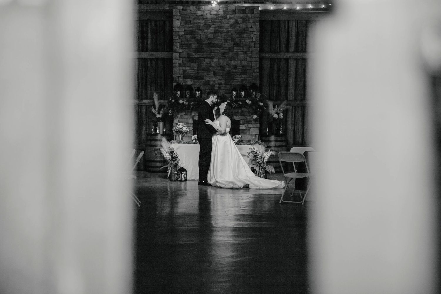 Black and white photo of bride and groom sharing first dance in rustic barn wedding venue in Huntsville, Alabama