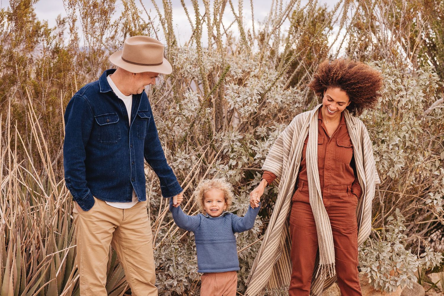 Family sitting on blanket under large tree during outdoor photo session.