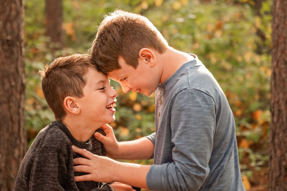 Two children sharing a playful moment together among fall trees.