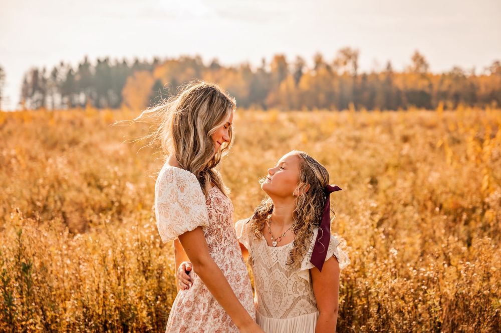 Two people share a romantic moment in a golden autumn field at sunset.