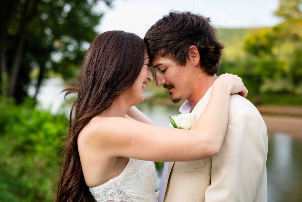 Bride and groom embracing with the Buffalo River behind them at their Arkansas riverside wedding