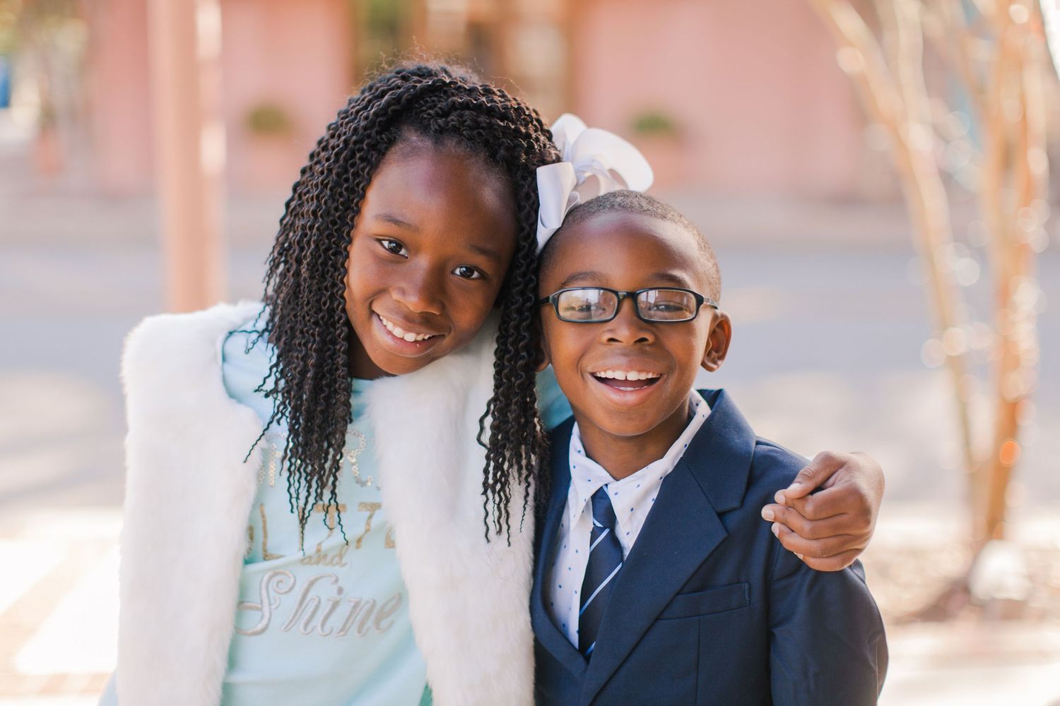 Two young students smiling together outdoors in casual and formal attire.