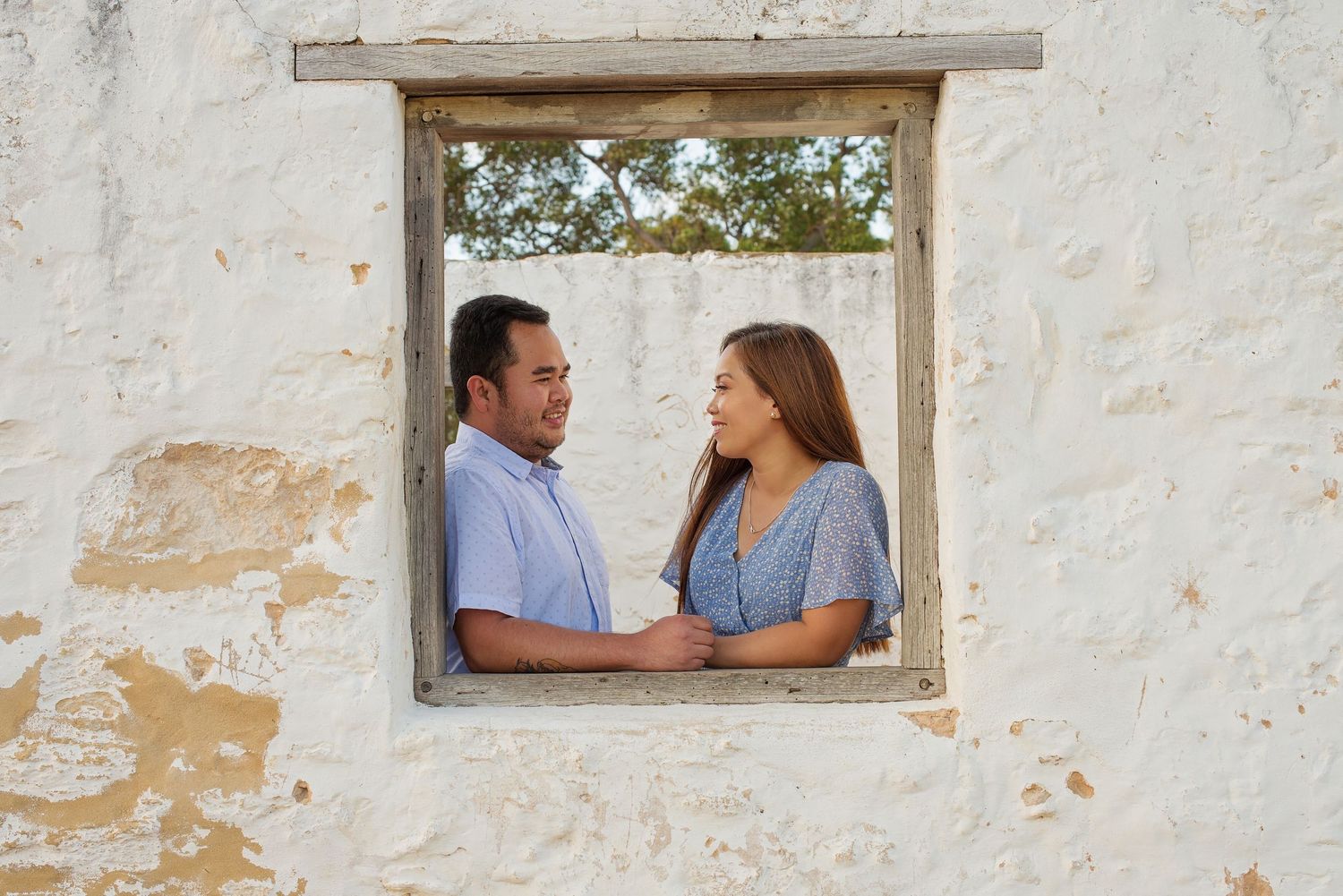 couple facing eachother standing in a window frame