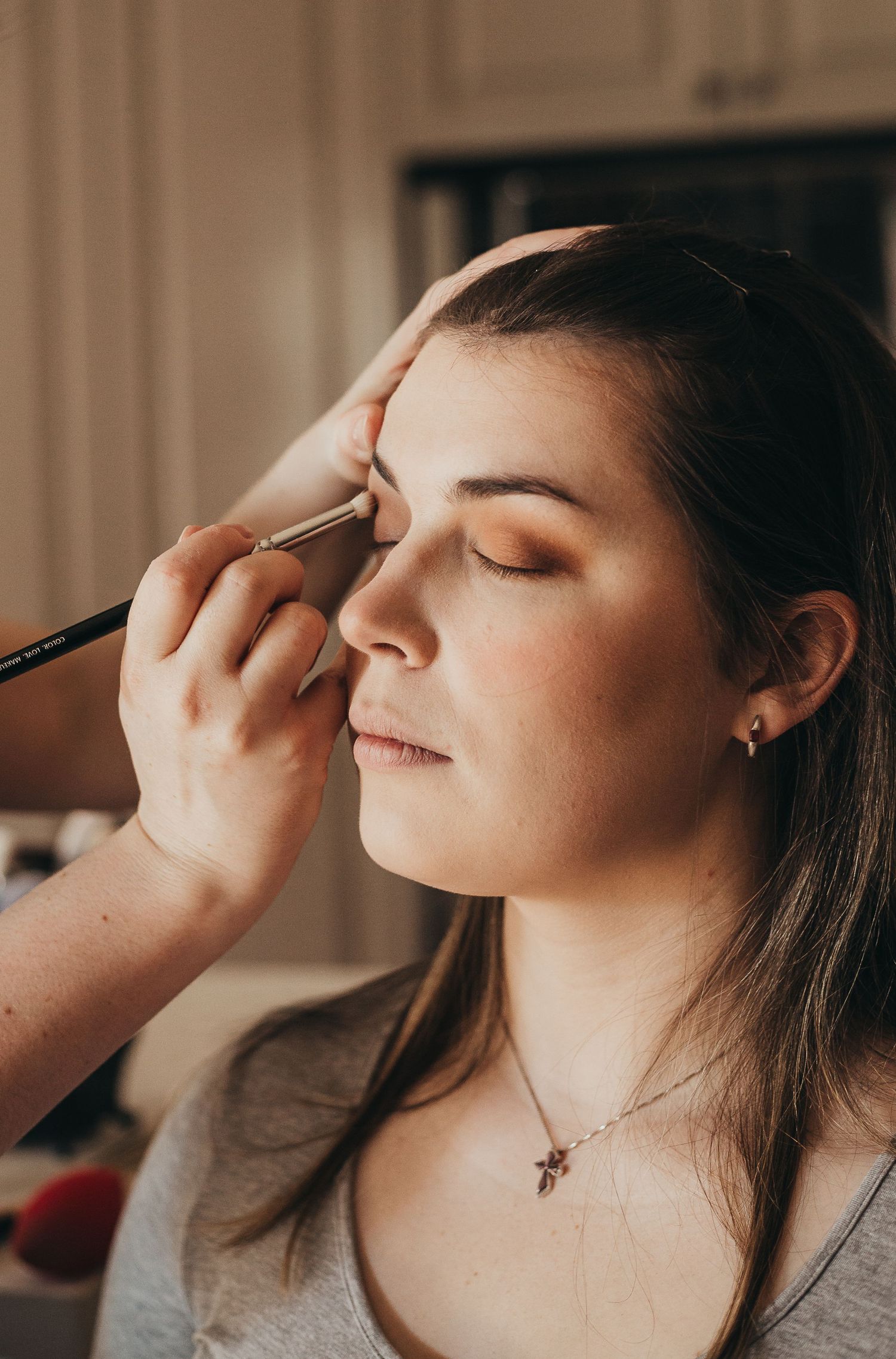 Close-up of eyebrow makeup application using a thin brush in warm indoor lighting.