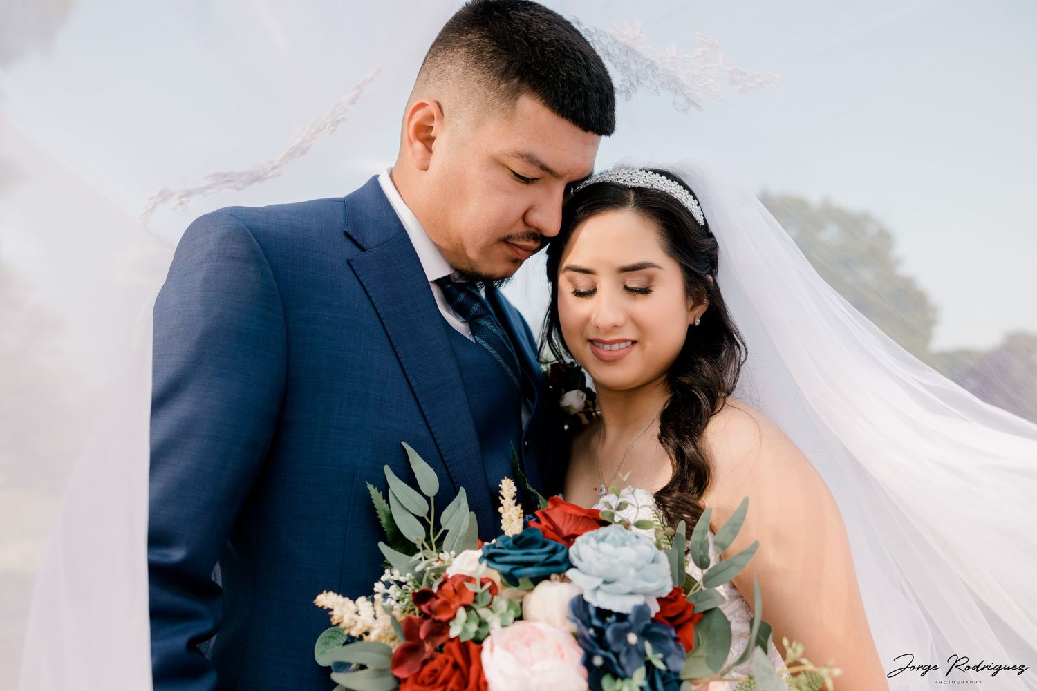 bridal photo with bride and groom looking down at the flower bouquet