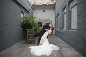 Wedding photos taken in an urban alley with grey painted walls.