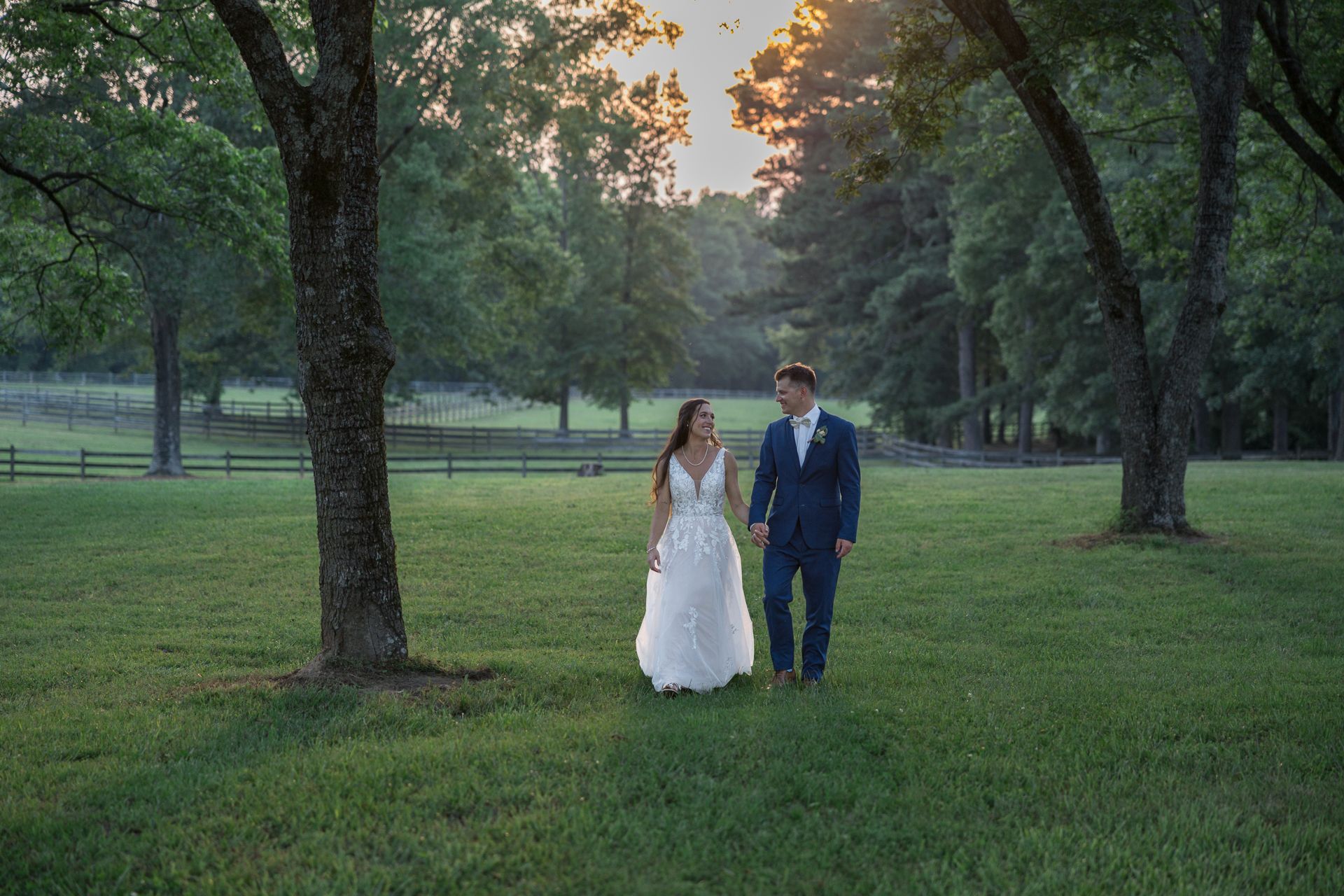 Couple walking together on a tree-lined path during golden hour sunset.