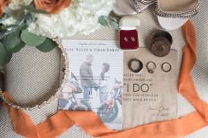 Wedding details including rings, invitations and decorative elements arranged on textured fabric.