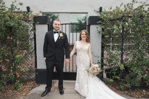 Wedding couple walking through garden pathway with blooming flowers.