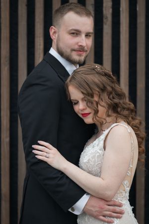 Intimate wedding portrait against wooden slat wall background.