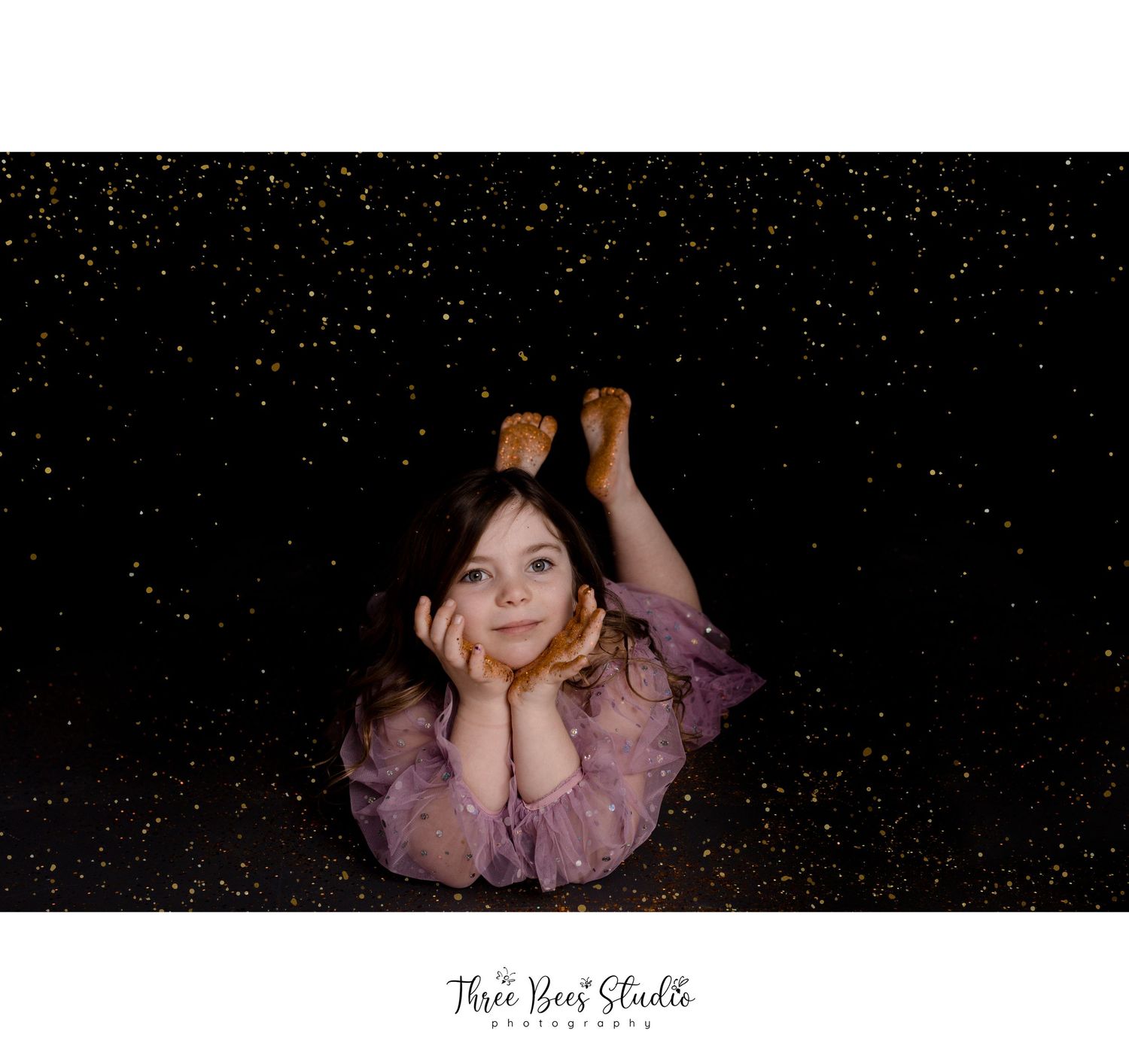 Dreamy portrait against starry black background with person in flowy mauve dress lying down.