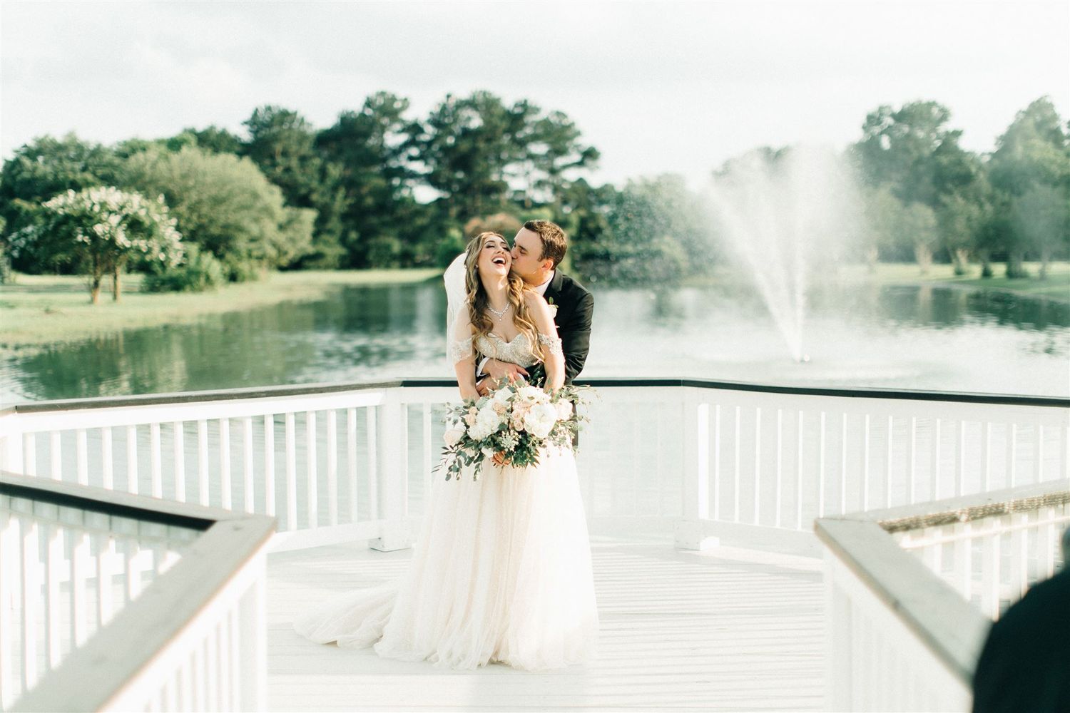 A dreamy waterfront wedding portrait with fountain spray and natural lighting.