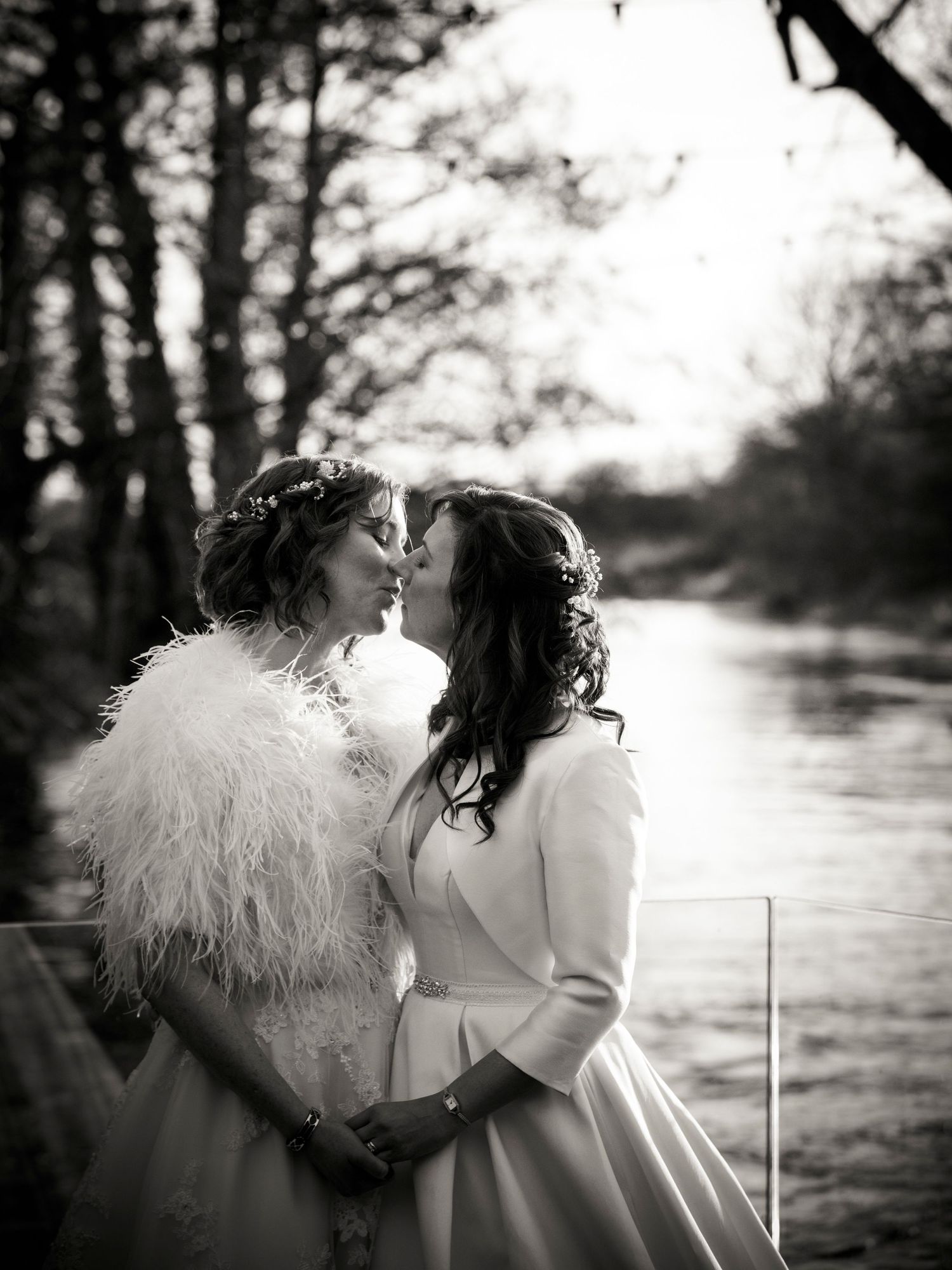 Black and white portrait of a romantic waterside wedding moment with feather wrap details.