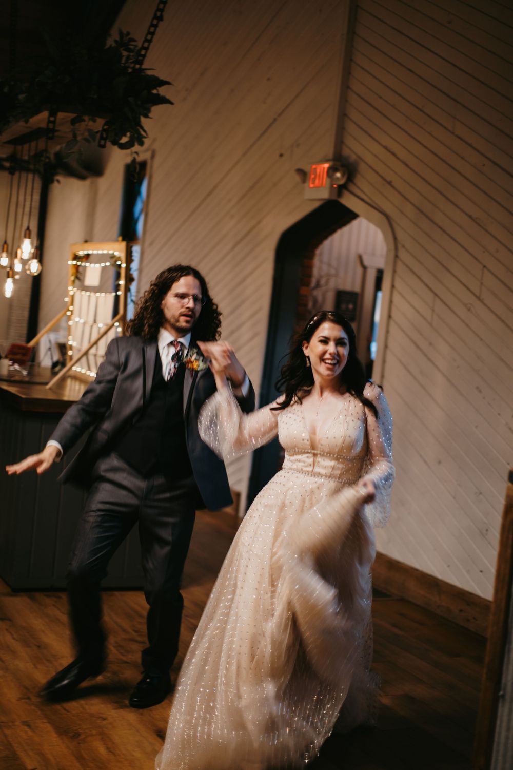 Bride and groom make a joyful grand entrance into their rustic barn wedding reception venue.