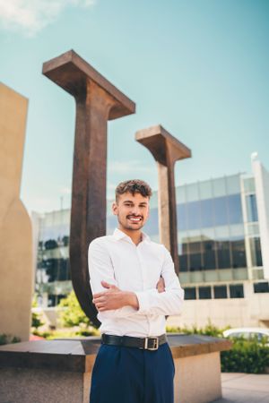 Professional portrait of someone in business attire standing in front of modern architecture.