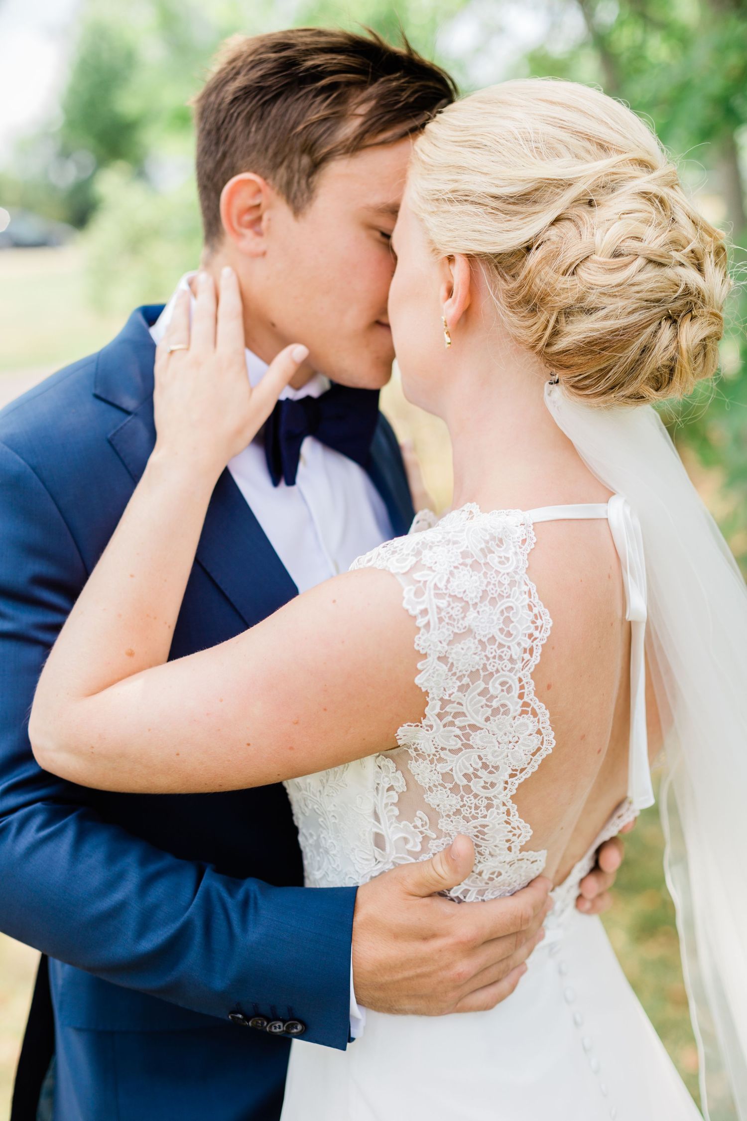 Romantic wedding kiss with bride in lace dress and groom in navy suit.