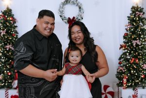 Family holiday photo session with Christmas trees and festive decorations in the background.