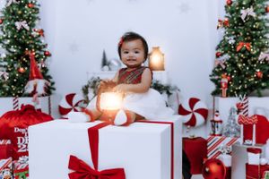 Christmas themed photo shoot with decorated trees and red holiday gifts.