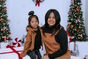 Family group poses playfully in front of Christmas trees and decorations.